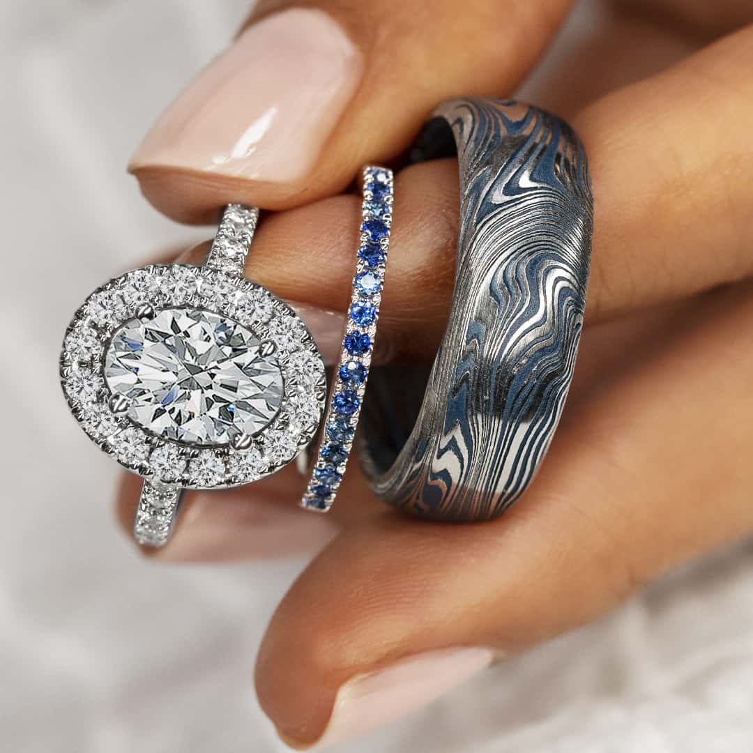 Damascus steel wedding band with navy blue cerakote detail paired with a white gold sapphire band