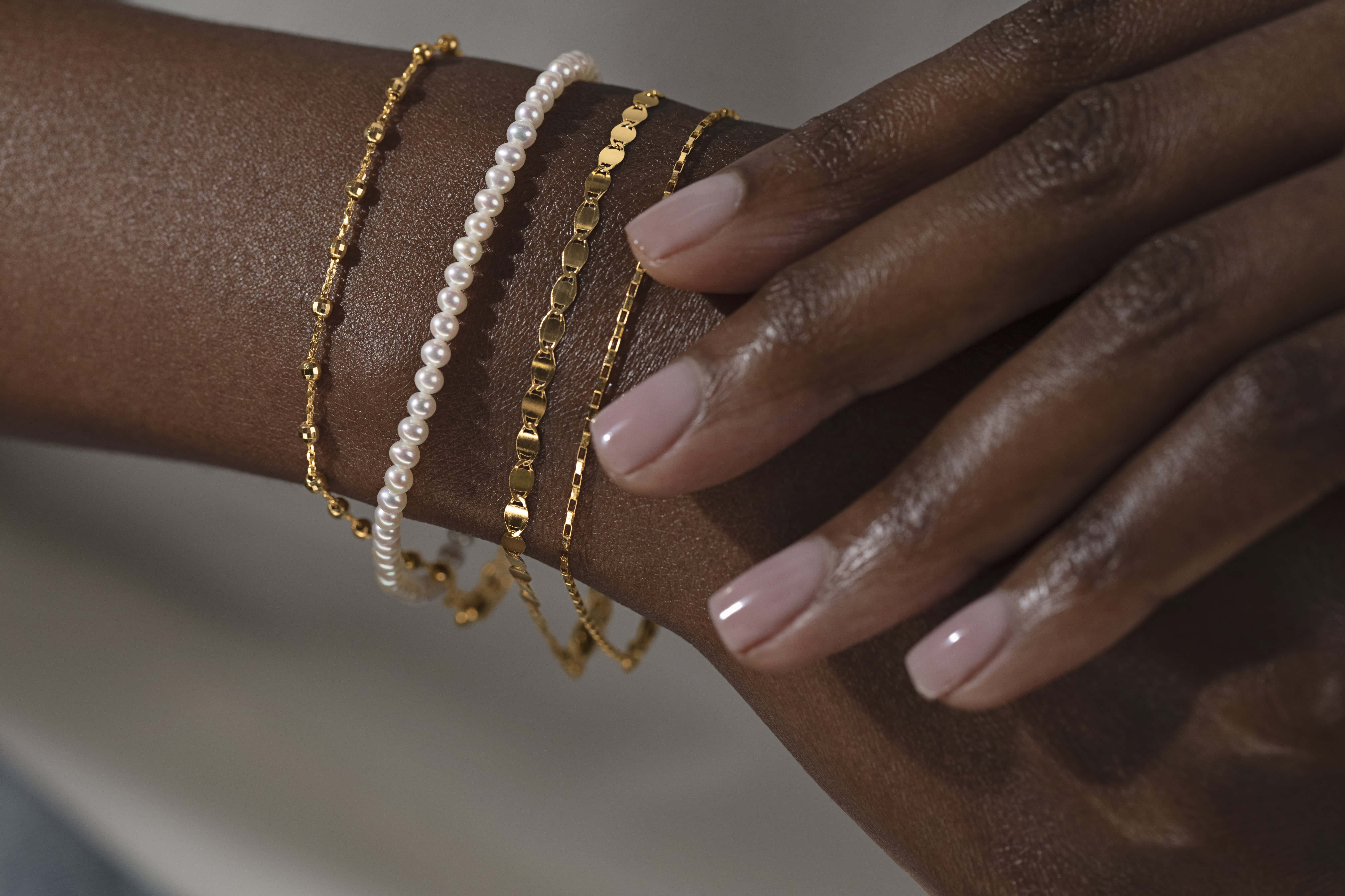 four 14k yellow gold bracelets including link, box, Valentino and cultured pearl styles